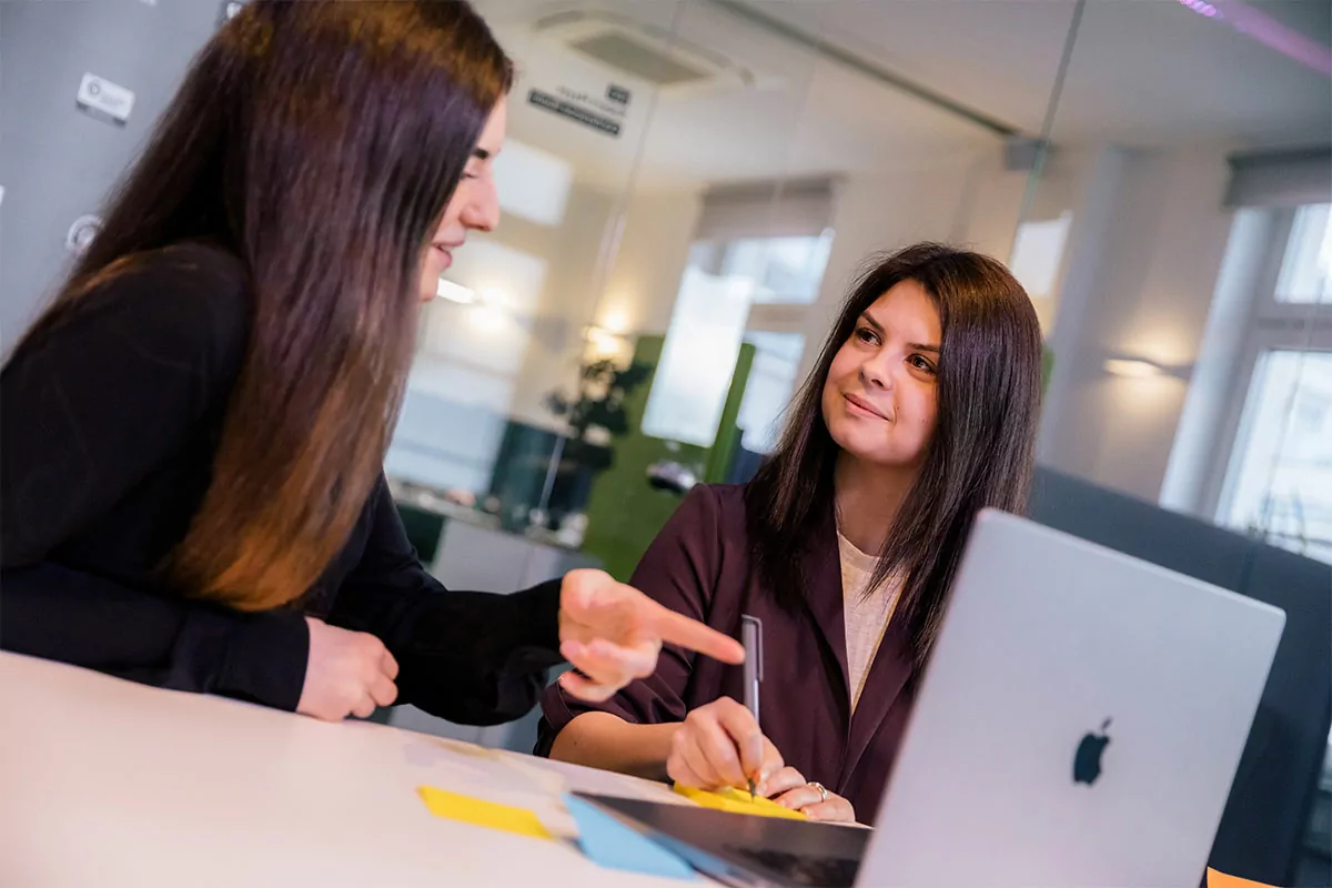 Zwei Mitarbeiter besprechen sich an ihrem Arbeitsplatz in der TYPO3-Agentur