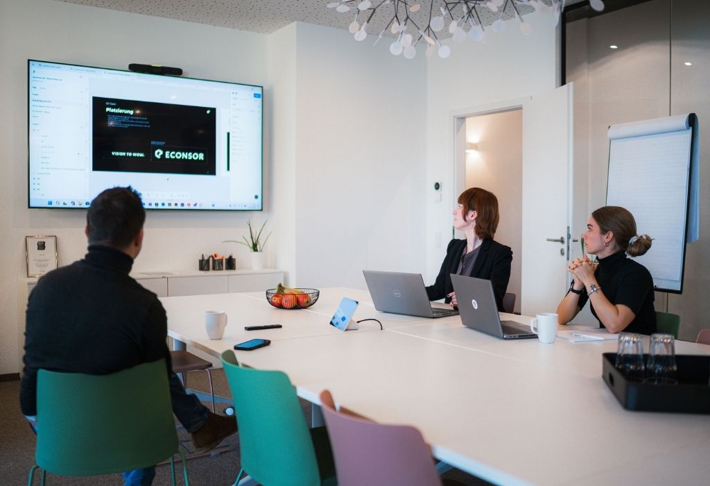 TYPO3 Besprechungsraum – Zusammenarbeit und Präsentation im Team Drei Personen im Besprechungsraum der Agentur ECONSOR arbeiten gemeinsam an einer Präsentation.